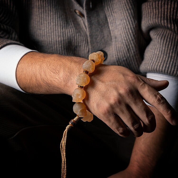 Hand wearing a beaded bracelet with a dark background
