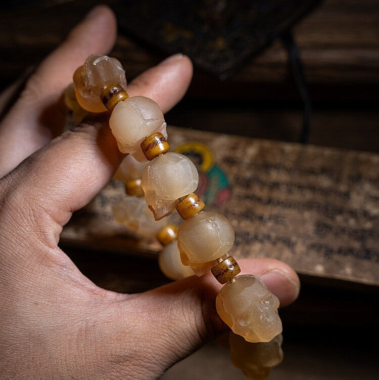 Hand holding a string of beige and brown beads against a blurred background