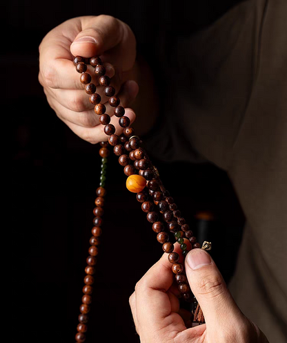 Person holding a wooden rosary against a dark background