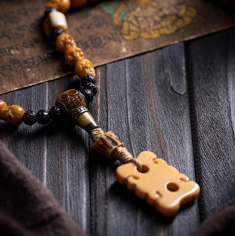 Close-up of a beaded necklace with a large decorative pendant on a textured surface.