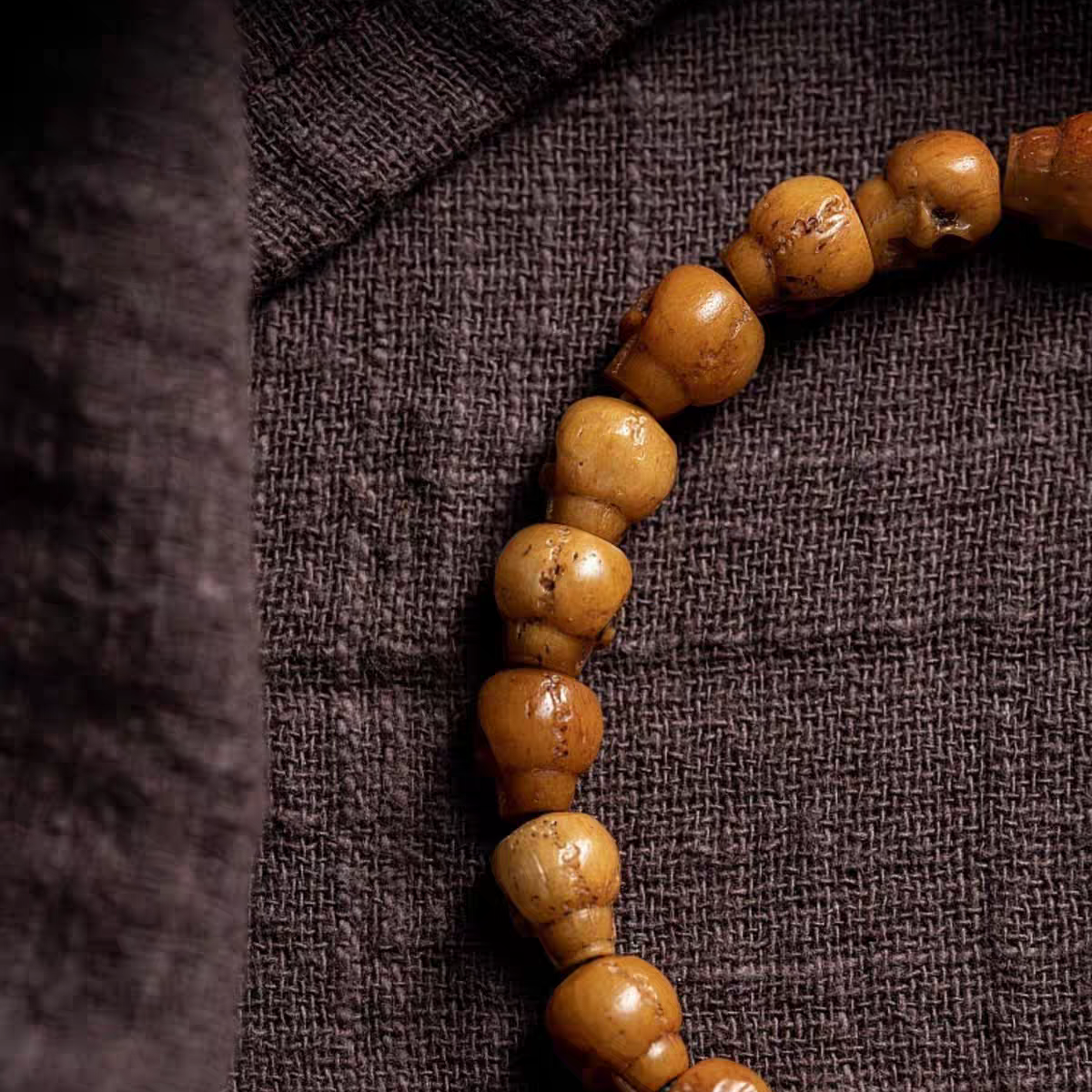 Brown beaded necklace on a textured brown fabric background