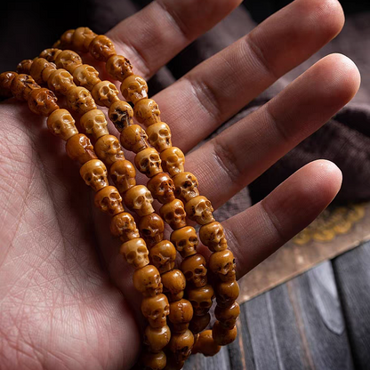 Hand holding a stack of brown beaded bracelets on a wooden surface