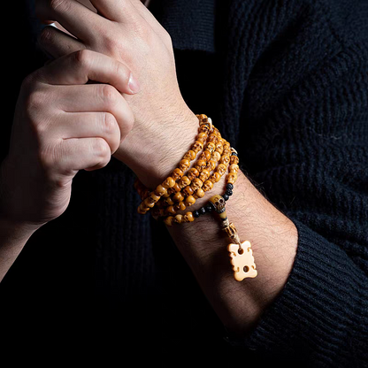 Close-up of a wrist with multiple bracelets and a key pendant on a dark background
