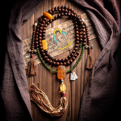 Wooden beaded necklace with tassels on a wooden surface with a cloth and a small painting.
